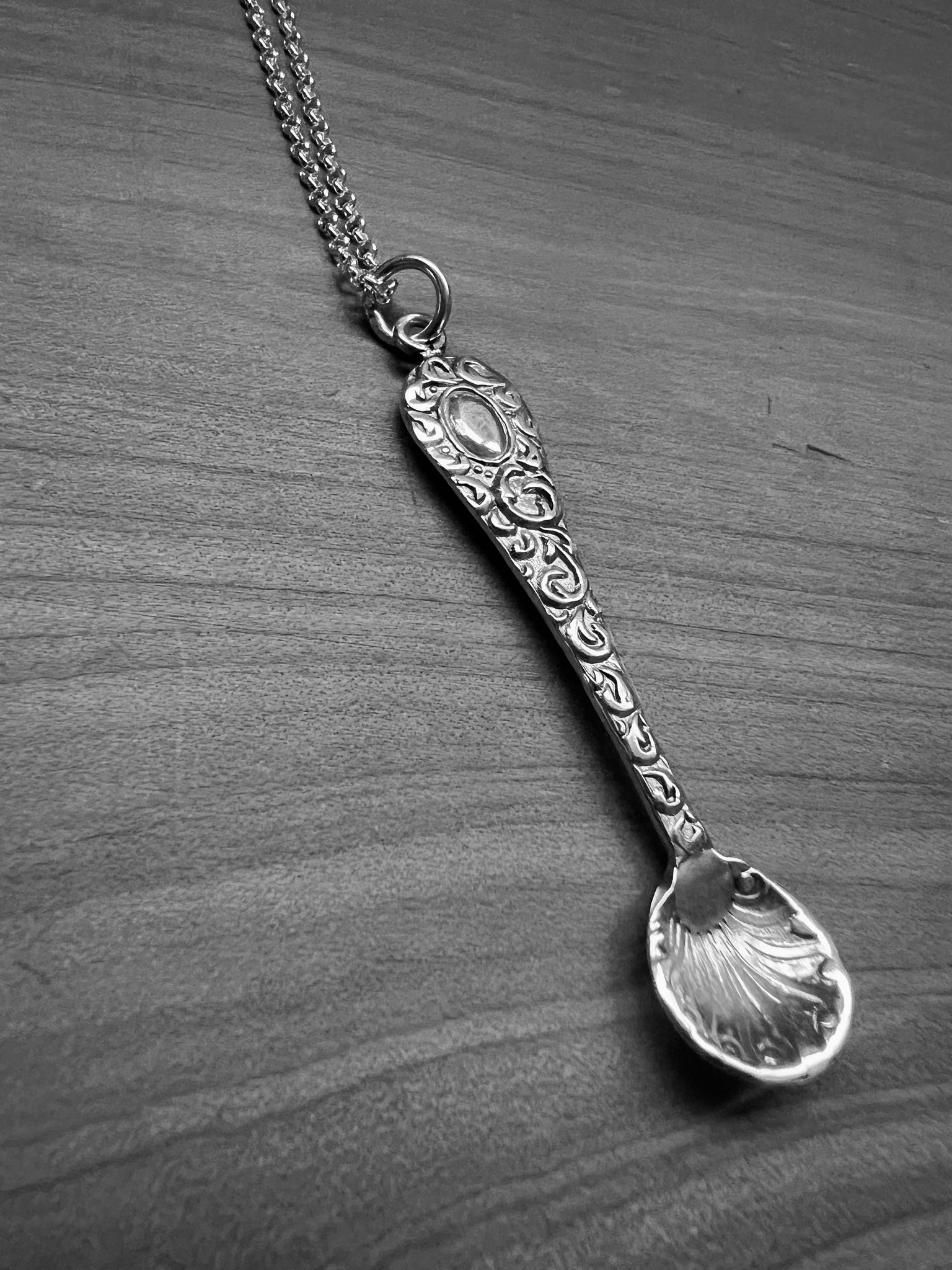 A tiny silver ornate salt spoon pendant upon sterling belcher chain