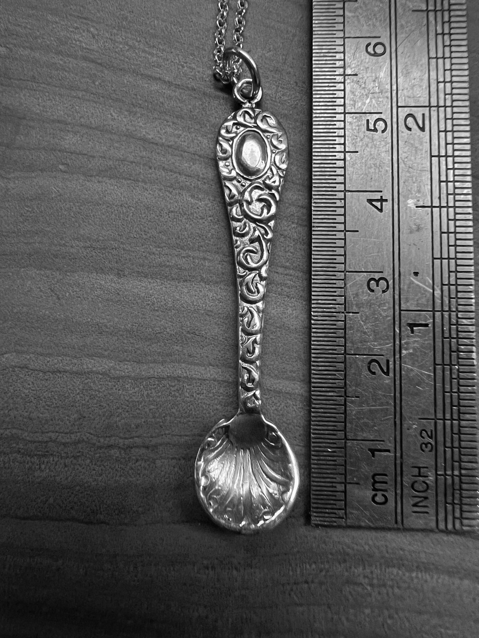 A tiny silver ornate salt spoon pendant upon sterling belcher chain